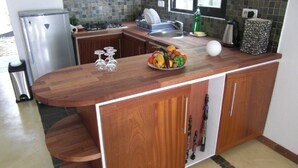 Een keuken met een houten kookeiland, roestvrijstalen apparatuur en een betegelde spatwand.