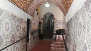 A hallway with patterned tiles, a red carpet, and a brick archway leading to a staircase. - Hotel Barranca 10 (San Miguel de Allende)