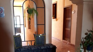 A hallway with a bench, potted plants, and a door with a number. - Hotel Barranca 10 (San Miguel de Allende)
