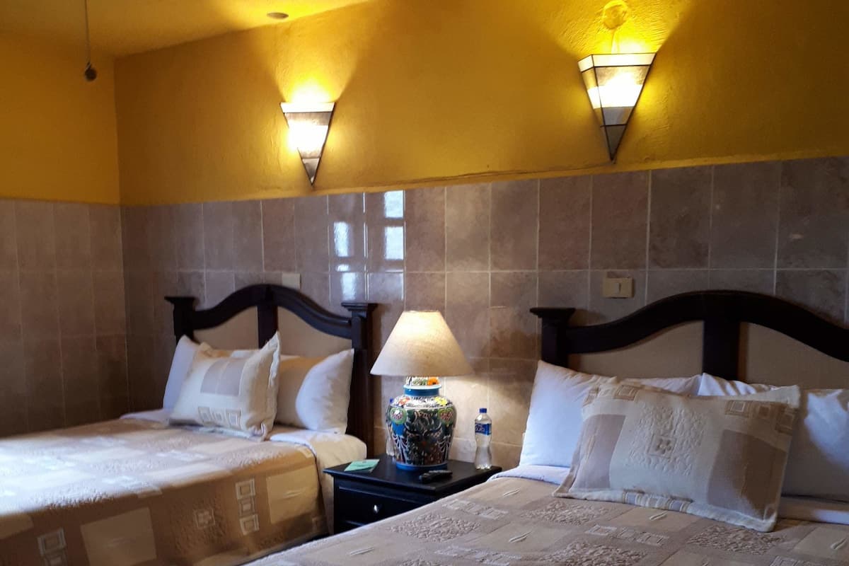 Ein Hotelzimmer mit zwei Betten, einem Nachttisch, einer Lampe und zwei Wandleuchten.