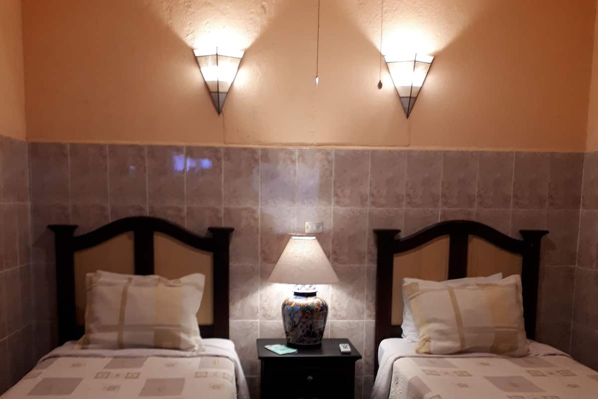 Ein Hotelzimmer mit zwei Betten, einem Nachttisch mit einer Vase und Wandleuchten.