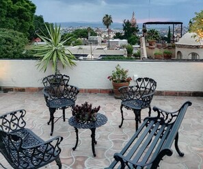 A rooftop terrace with outdoor furniture, potted plants, and a view of a cityscape. - Hotel Barranca 10 (San Miguel de Allende)