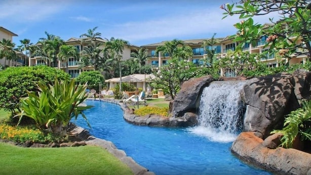 A resort with a swimming pool, a waterfall, and lush greenery.