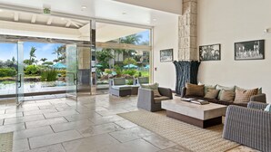 A spacious lobby with a large glass door leading to an outdoor area, furnished with sofas and a coffee table.