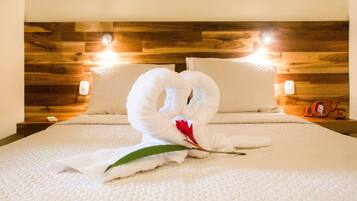 Une chambre d’hôtel avec une tête de lit en bois, deux oreillers et un lit recouvert d’une courtepointe blanche à texture.