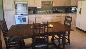 A kitchen with wooden cabinets, a stove, and a dining table with chairs. - Cozy beach cottage in Magnolia (Port Lavaca)