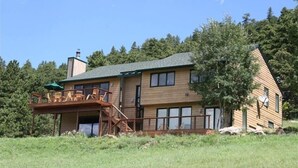 Une maison en bois à deux étages, dotée d’un balcon et d’une cheminée.