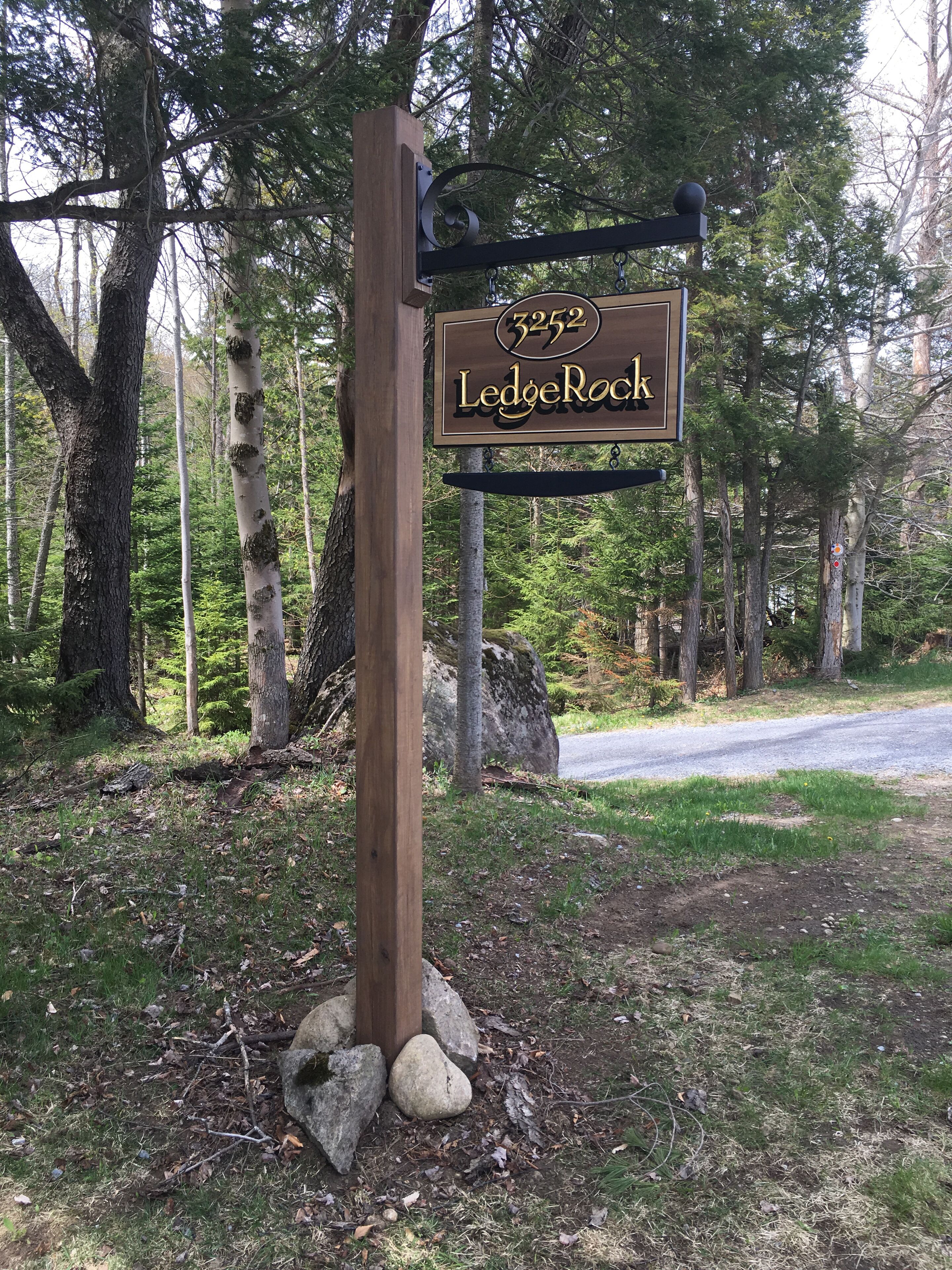 Un senyal de fusta amb la paraula 'LedgeRock', envoltat d'arbres i un camí de grava.