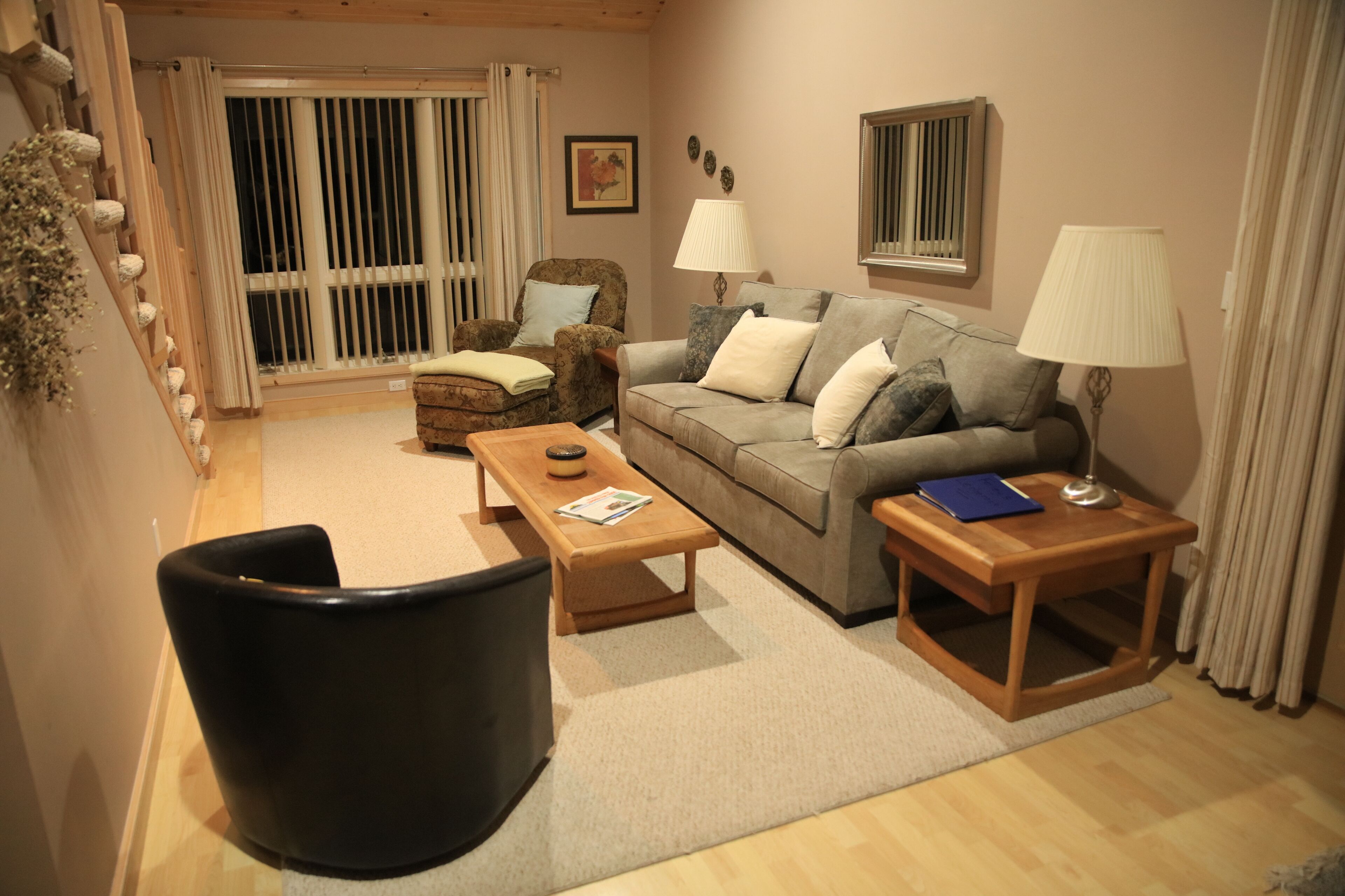Een gezellige woonkamer met een bank, fauteuils, een salontafel en lampen.