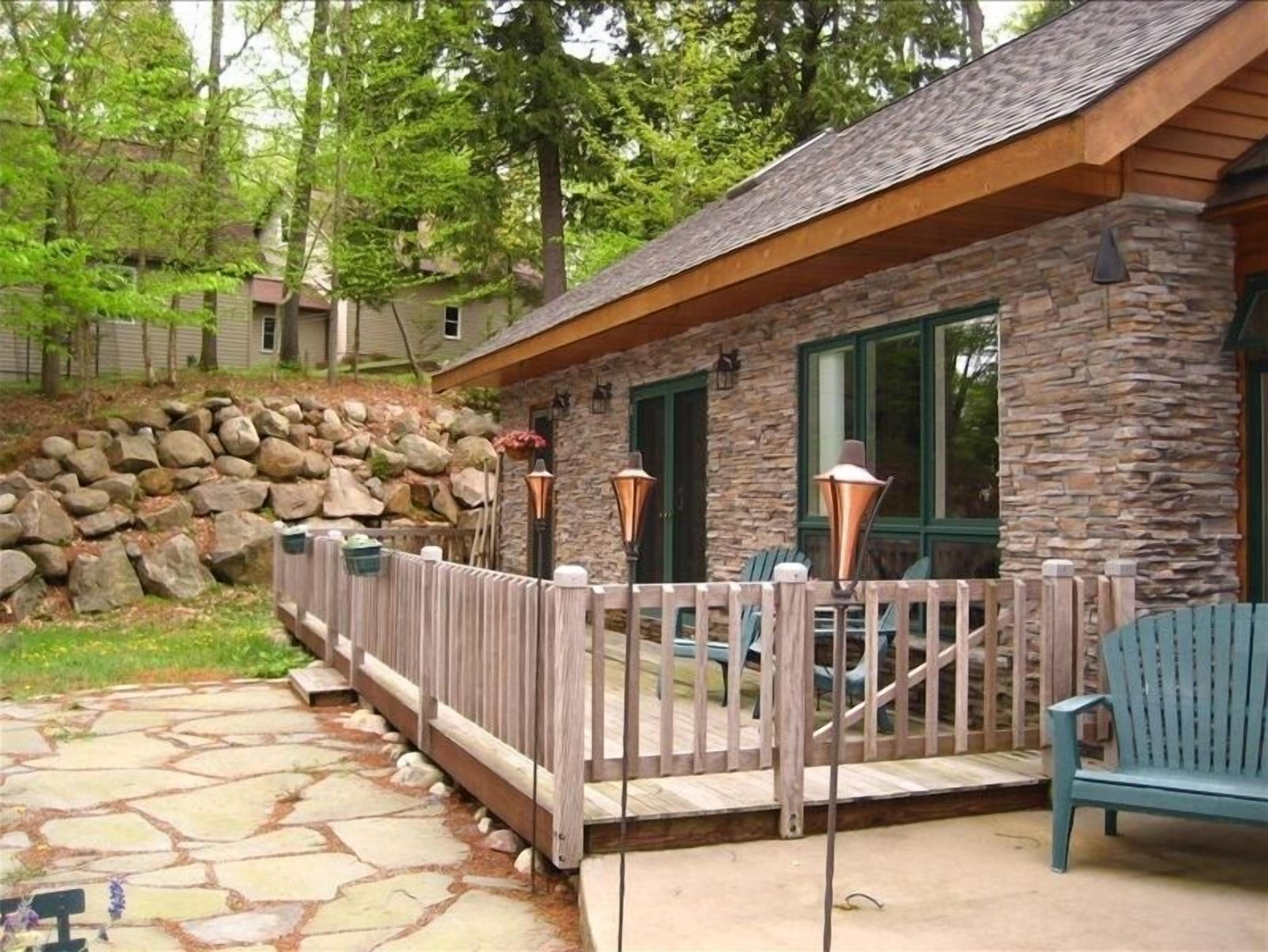 A stone house with a wooden deck, stone steps, and a stone wall.