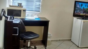 A compact room with a desk, a chair, a microwave, a refrigerator, and a television. - Madero Suites (Coatzacoalcos)