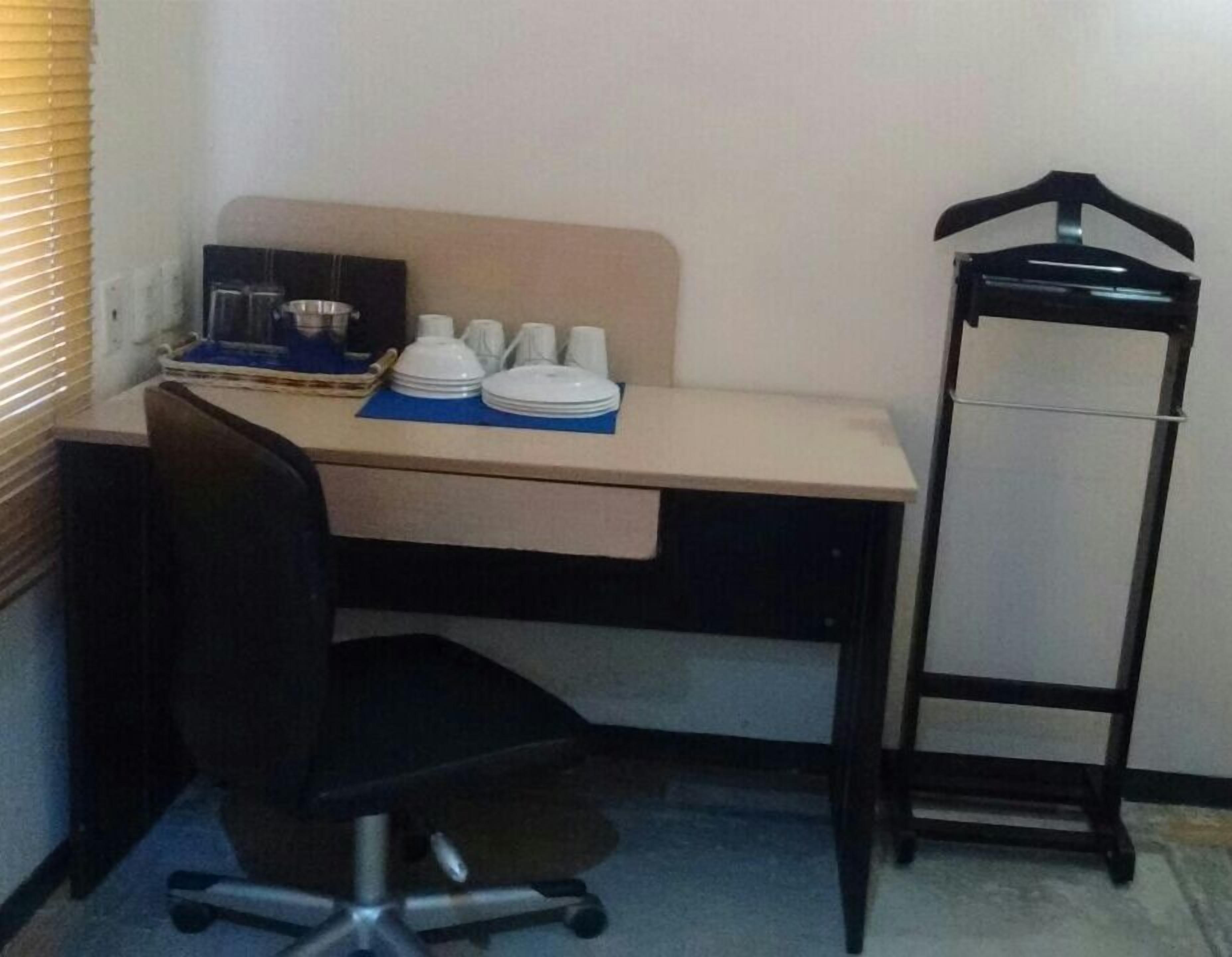 Un espacio de oficina pequeño con un escritorio, una silla y un perchero.