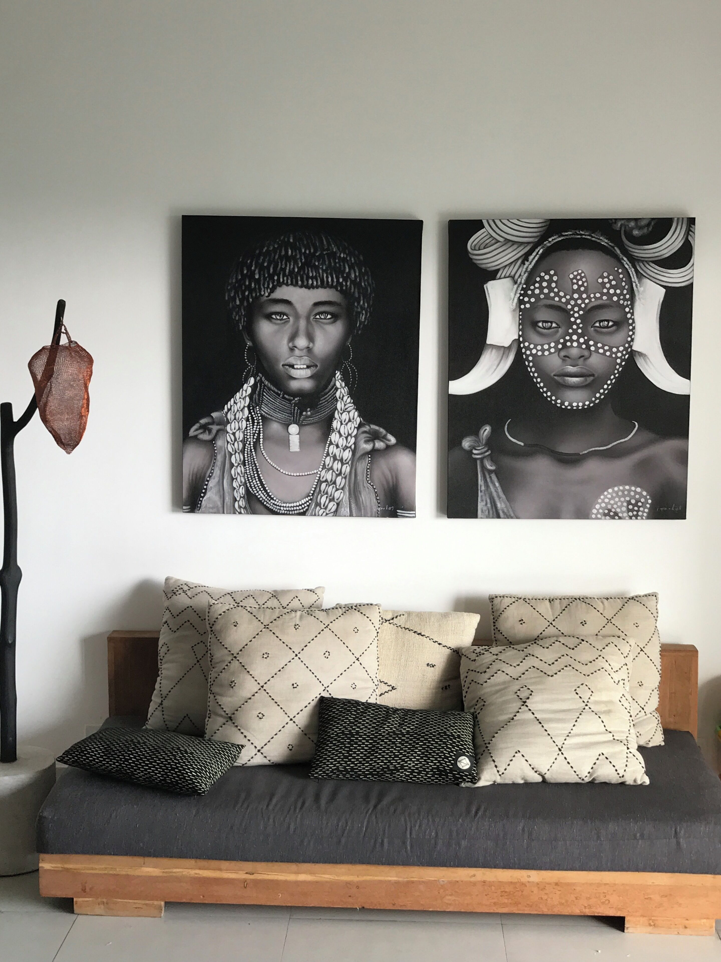 A modern living room with a sofa, patterned cushions, and two black and white paintings on the wall.