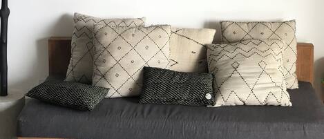 A modern living room with a sofa, patterned cushions, and two black and white paintings on the wall.