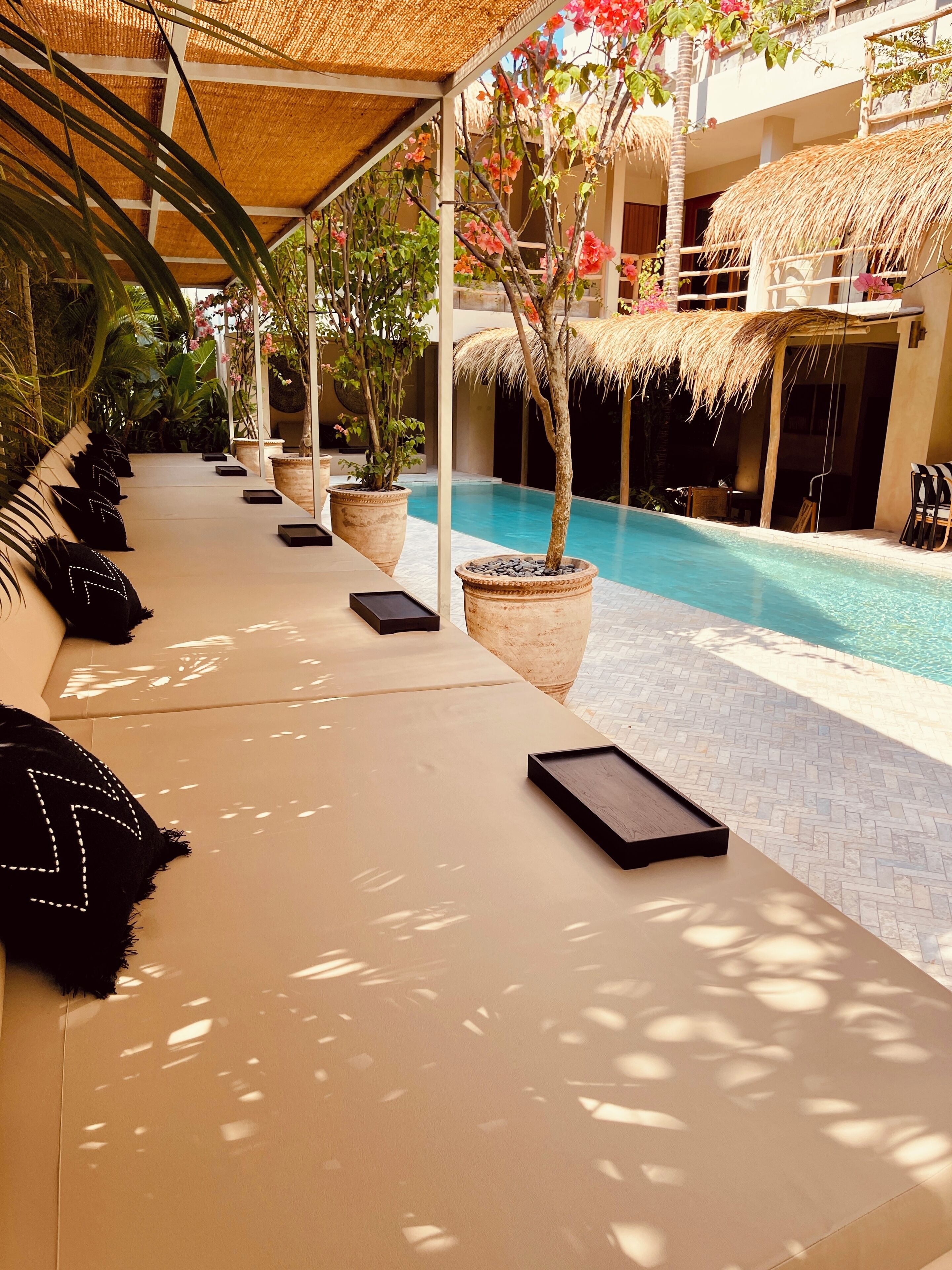 A poolside lounge area with sun loungers, potted plants, and a clear view of the pool.