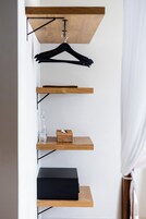 Una habitación minimalista con una estantería de madera, una caja negra y una botella de vidrio.