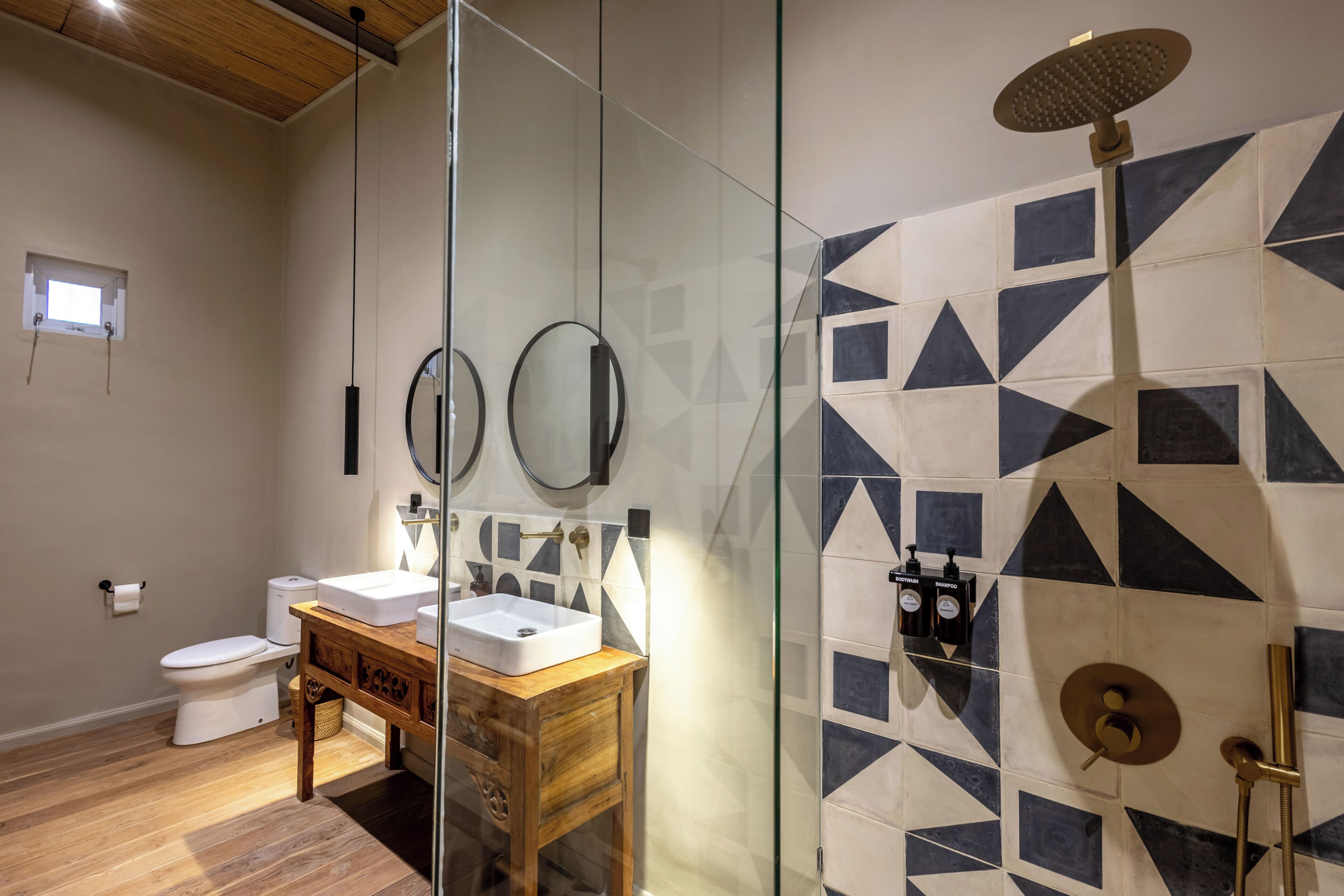 A modern bathroom with a glass shower enclosure, a wooden vanity with a sink, and a toilet.