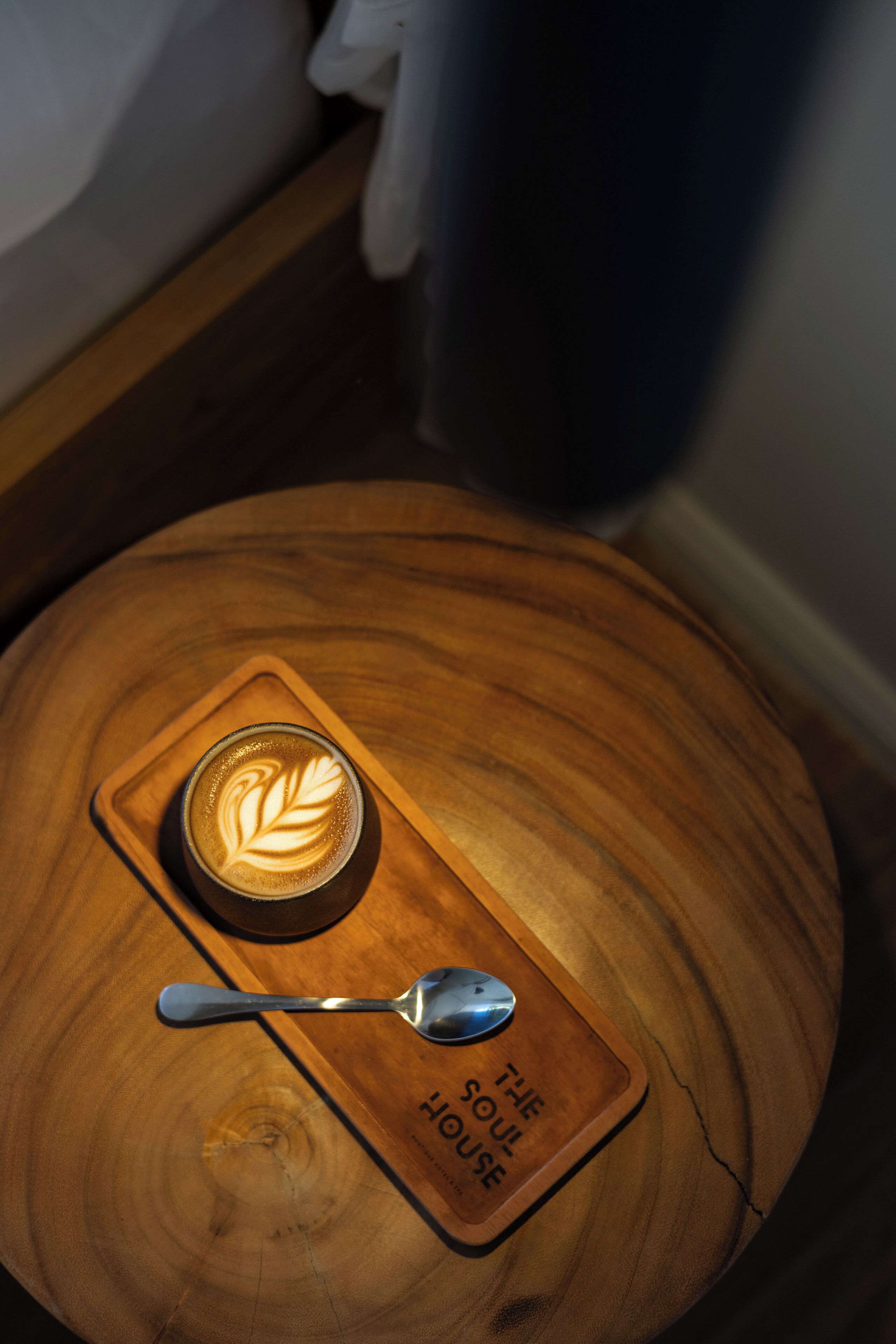 A wooden table with a coffee cup and spoon, and a placemat with 'THE SOUL HOUSE' text.