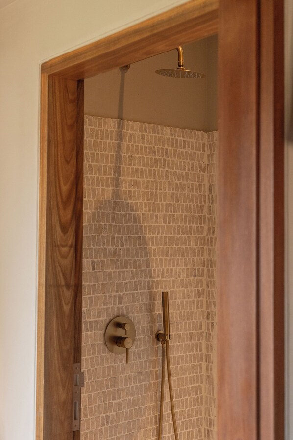 Ducha con estructura de madera, pared con azulejos y rociador.