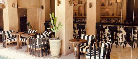 A poolside area with outdoor seating, a bar, and a large potted plant.