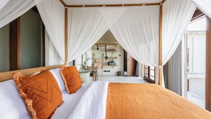 A bedroom with a bed, white curtains, and a view of a room with a plant and a table. - The Soul House Bali (Canggu)
