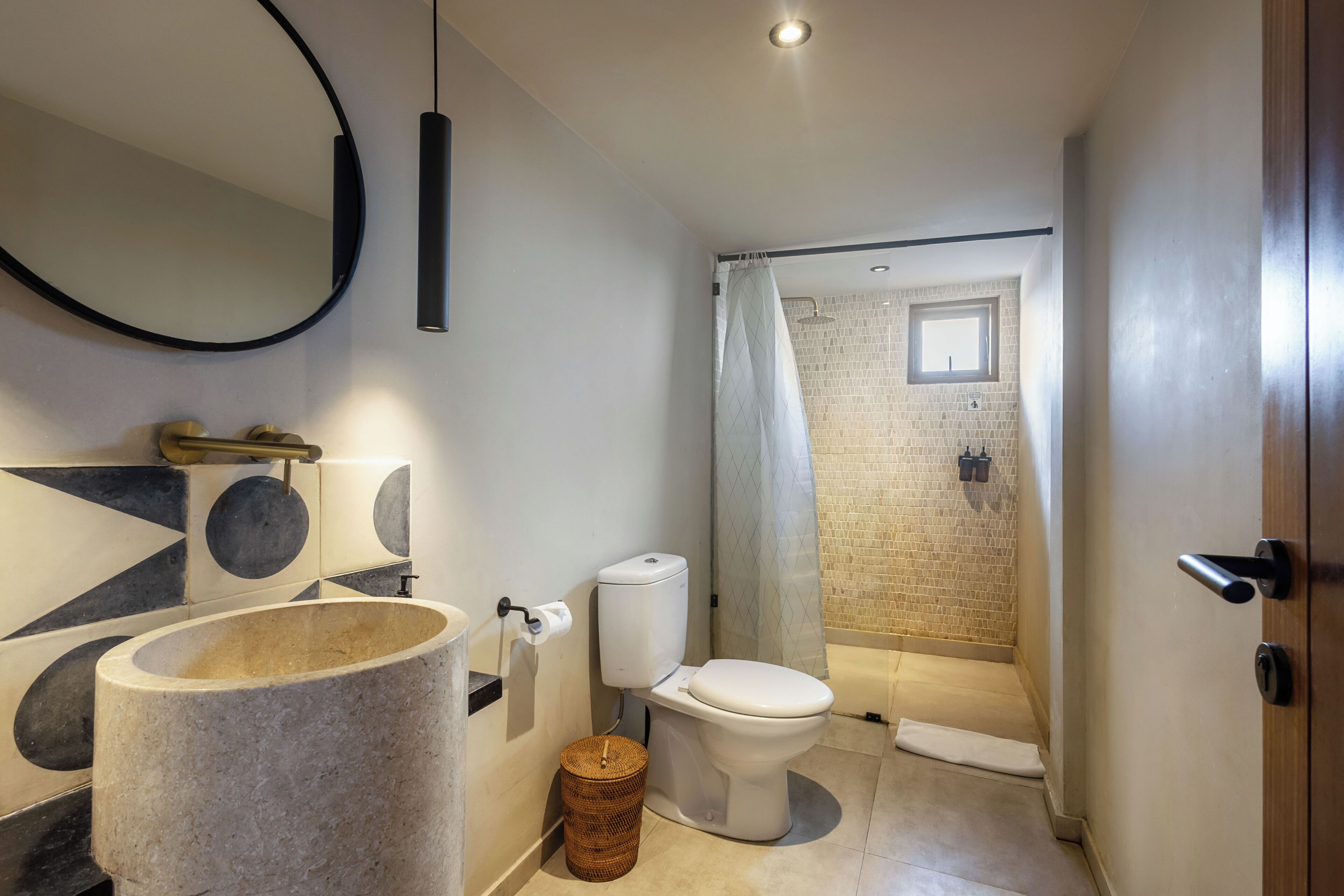 Une salle de bain au design moderne, comprenant un lavabo en pierre, des toilettes et un espace douche.