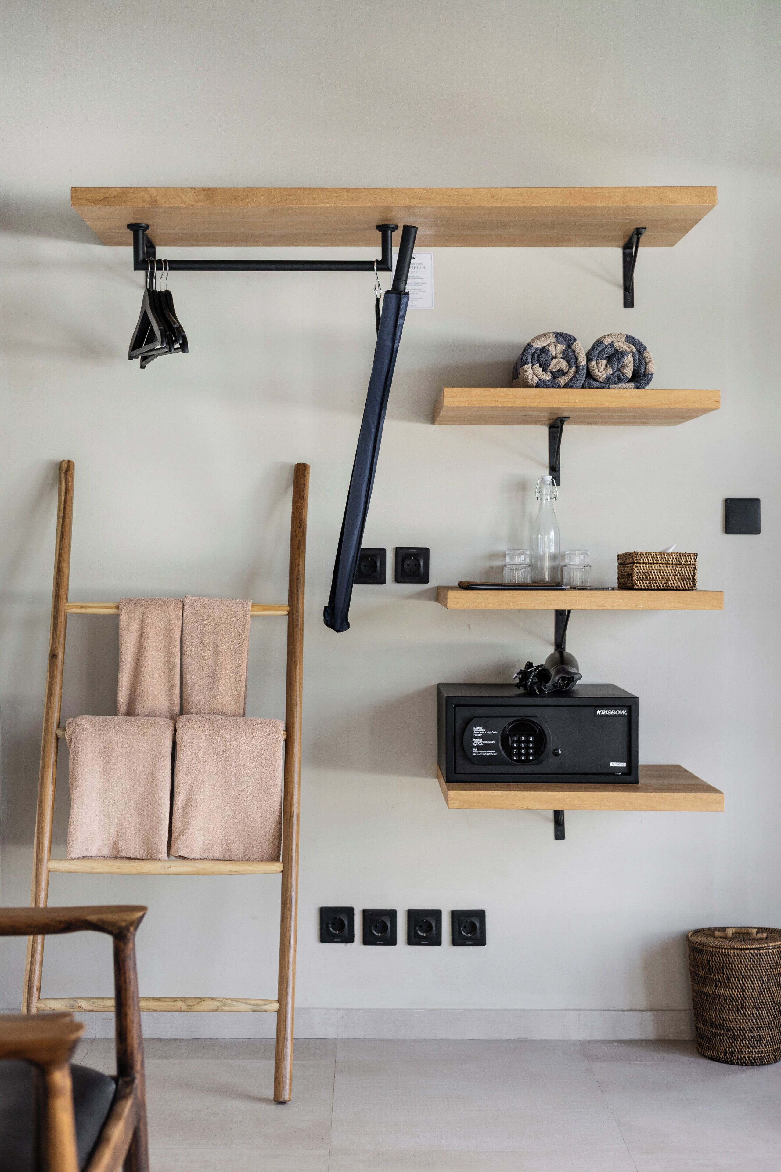 A room with a wooden ladder, a shelf with a speaker, and a woven basket.