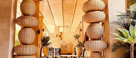 Entrada a un resort tropical con techo de paja, decoración de mimbre y baldosas estampadas.