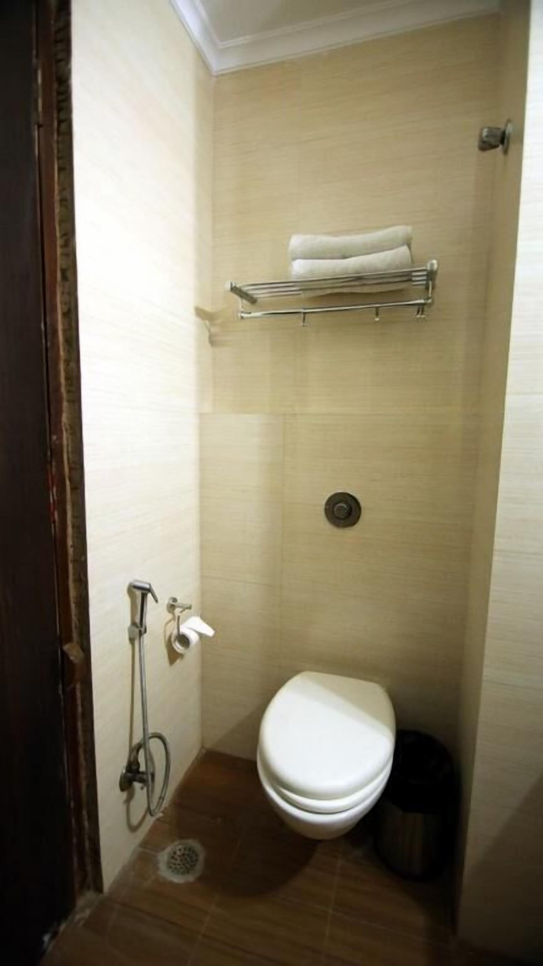 A small, compact bathroom with a toilet, a shower, and a towel rack.