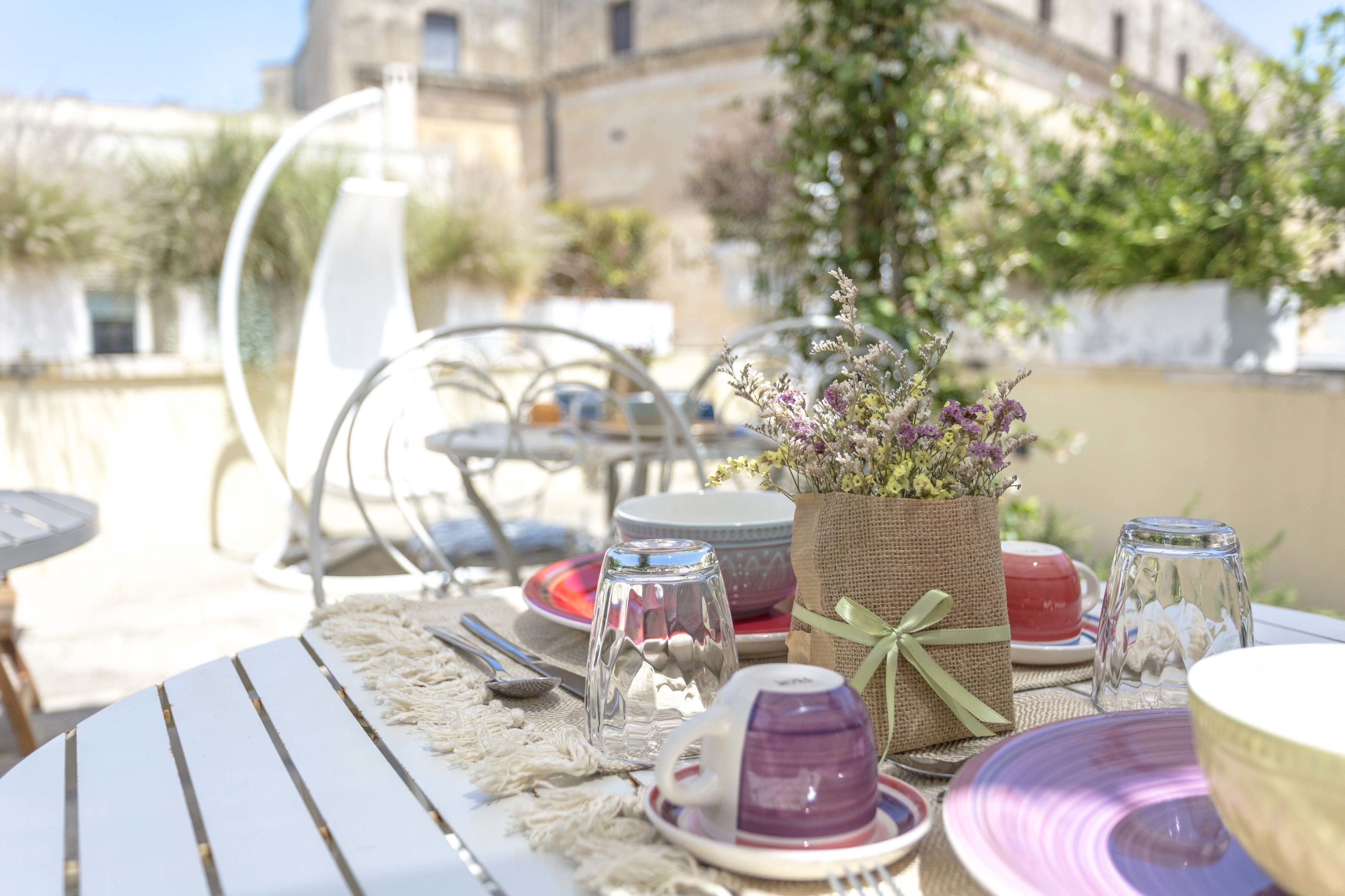 An outdoor dining area with tables set for a meal, featuring a variety of dishes and glassware.