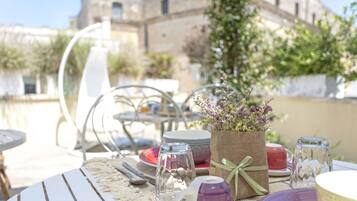 An outdoor dining area with tables set for a meal, featuring a variety of dishes and glassware.