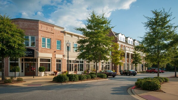A row of townhouses with brick facades, large windows, and a sidewalk with potted plants. - The Inn at Patrick Square (Clemson)