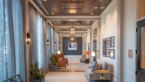 Un hall d’hôtel avec un long couloir, des espaces de détente et un comptoir d’accueil.