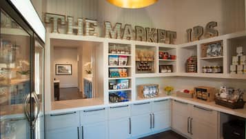 A kitchen with white cabinets, a countertop with various items, and a sign that reads "THE MARKET IPS".