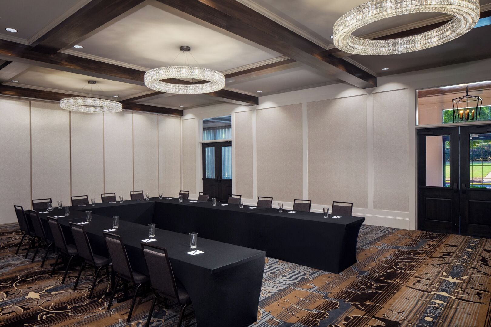 Une salle de conférence avec une longue table, des chaises et deux lustres.