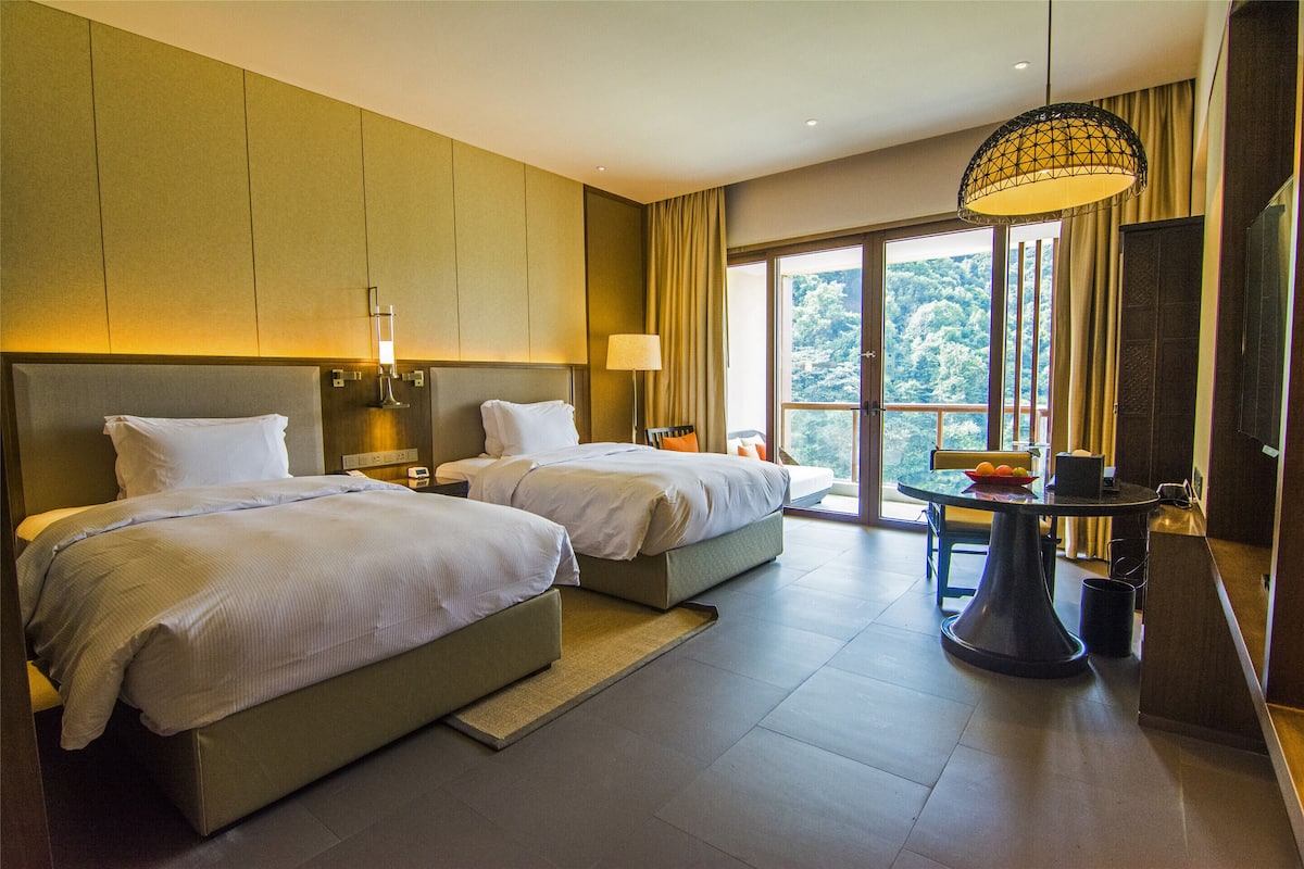 Une chambre d’hôtel avec deux lits, une table à manger et une vue sur l’extérieur.