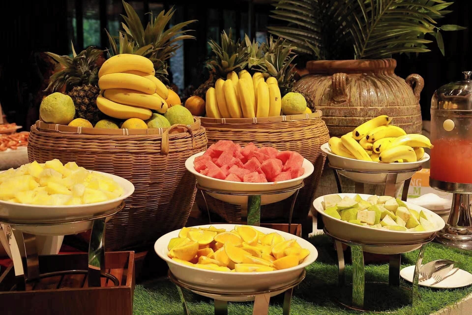 A buffet with various fruits and a beverage dispenser.