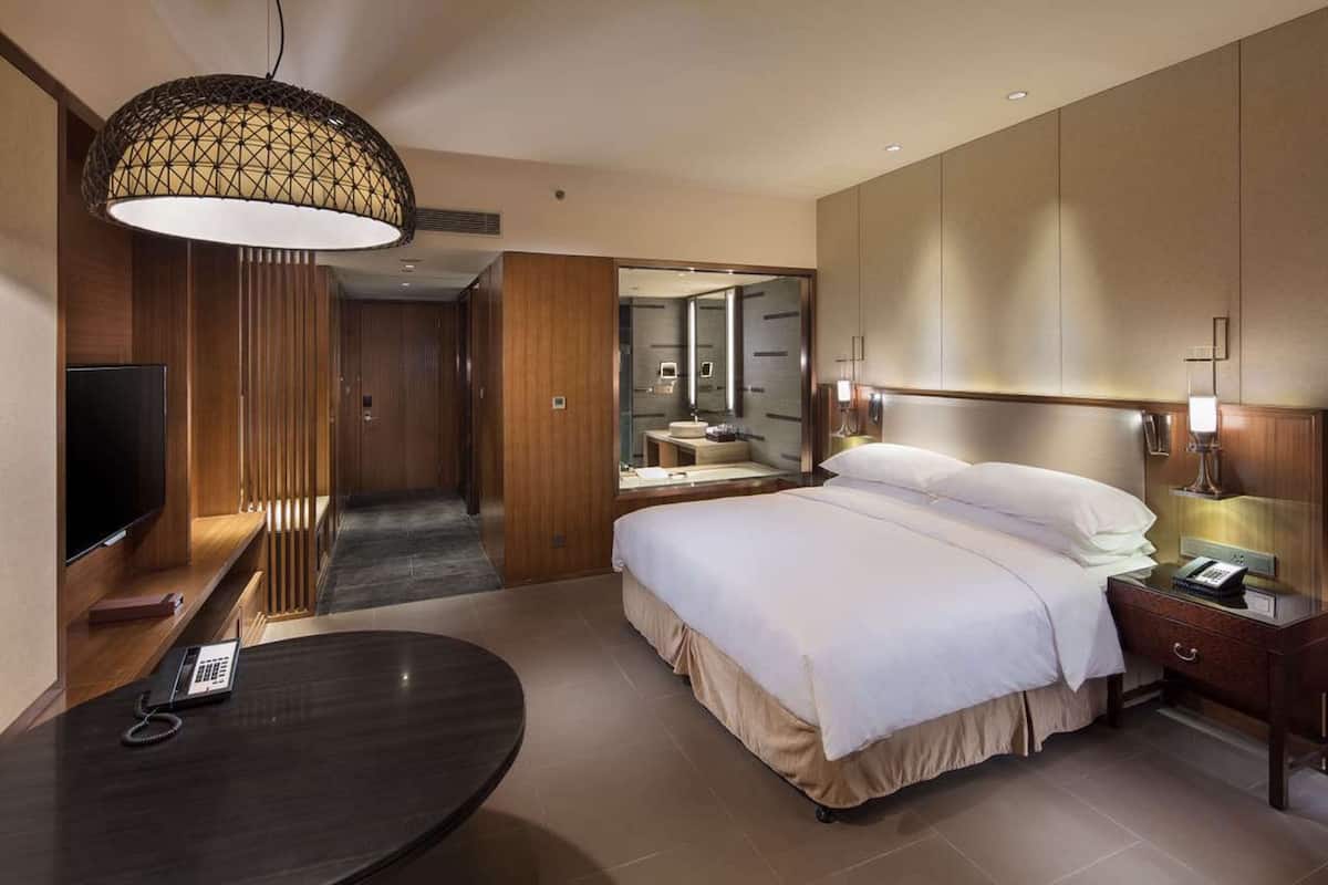Une chambre d’hôtel équipée d’un lit, d’une table de chevet, d’une lampe et d’un téléviseur.