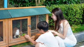 Zwei Personen interagieren mit einem Gehege für Tiere aus Holz.