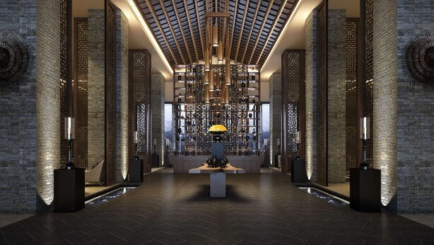Een moderne lobby met een hoge plafond, behang met patroon en een decoratieve lamp in het midden.