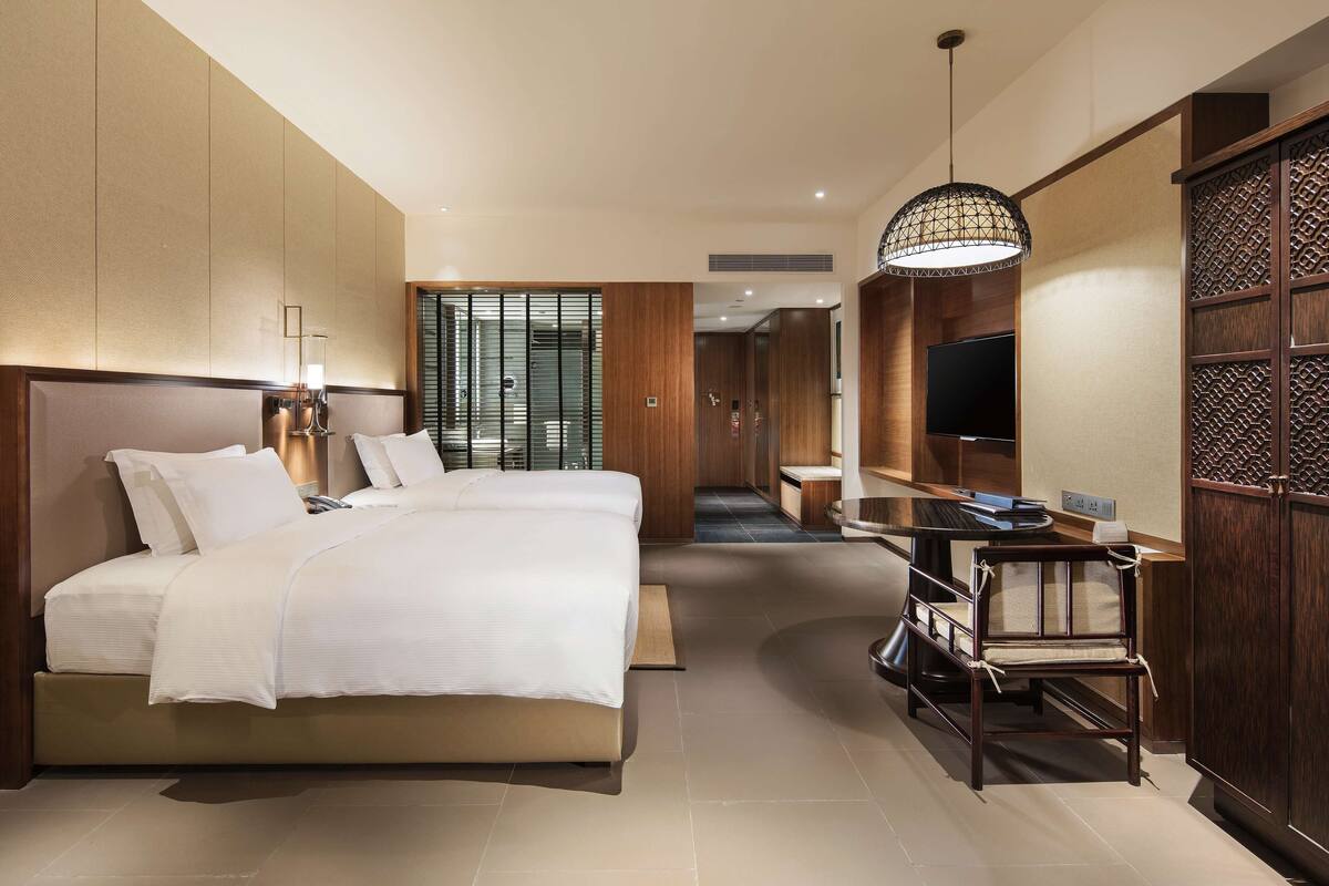 Une chambre d’hôtel moderne dotée d’un grand lit, d’un bureau avec une chaise, d’une télévision et d’un panneau décoratif mural.