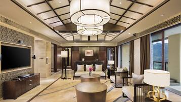 A spacious hotel lobby with a large flat-screen TV, a sofa, a coffee table, and a chandelier.