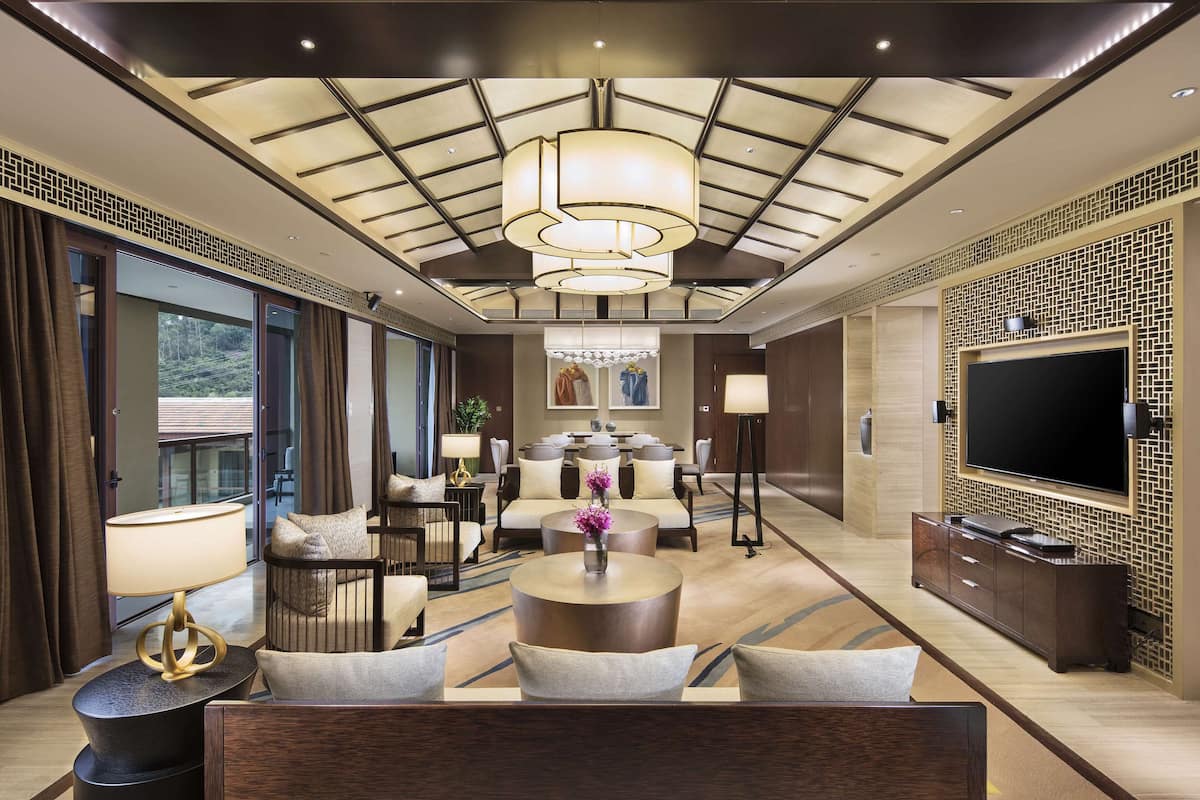 Un hall d’hôtel moderne doté d’un grand lustre, d’un espace salon et d’un téléviseur à écran plat.