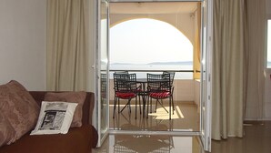 A room with a sofa, a glass door leading to a balcony with chairs and a view of the sea. - Family apartment with sea view and heated swimming pool ap8 (Okrug Gornji)