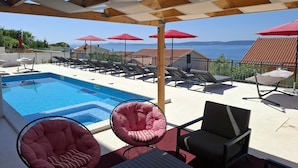 A poolside area with a clear view of the sea, lounge chairs, and umbrellas. - Family apartment with sea view and heated swimming pool ap8 (Okrug Gornji)