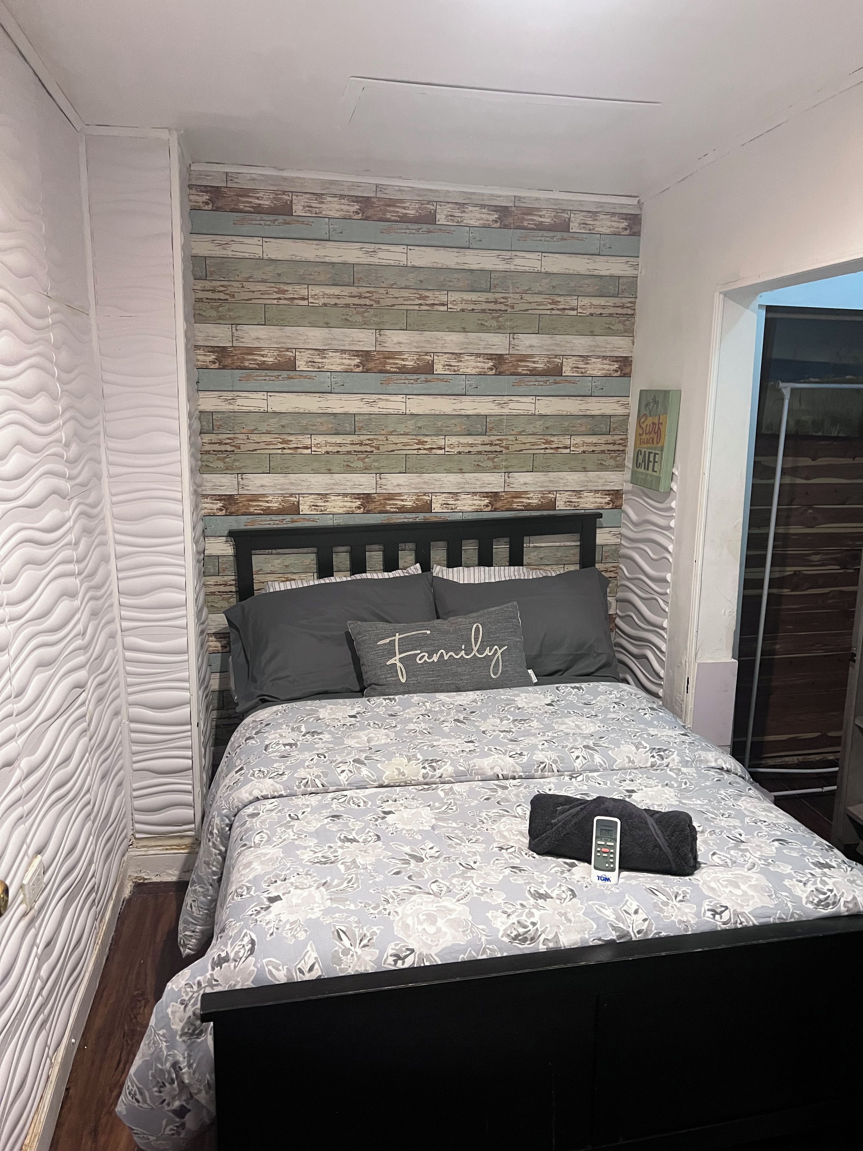 A bedroom with a bed, a wooden wall panel, and a sign indicating a cafe.