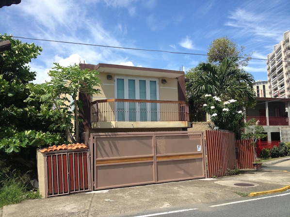A two-story building with a balcony, a gated entrance, and a red fence.