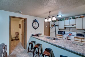 A kitchen with a granite countertop, a sink, a stove, and a microwave. There are three wooden stools and a clock on the wall. - Ski get away 10 minutes to Terry Peak★Deadwood★ Local Brewery across st (Lead)