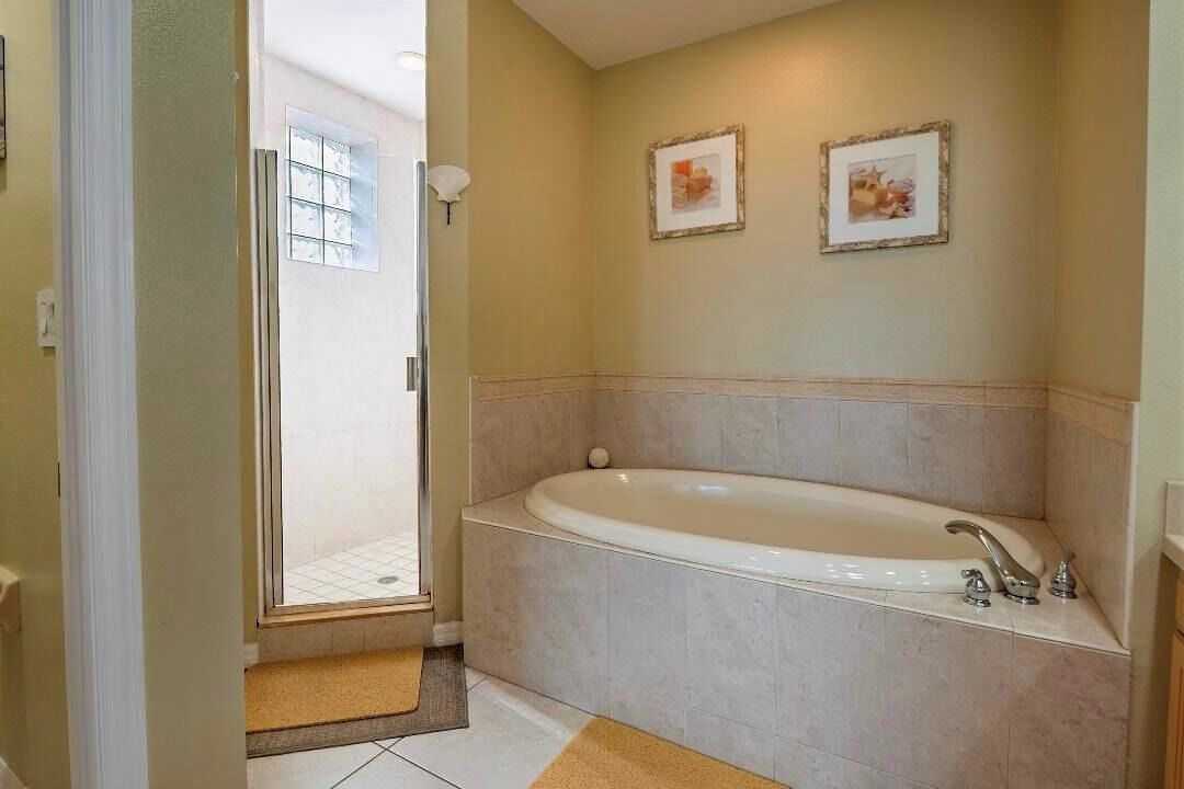 Une salle de bain avec une baignoire, un espace douche et deux tableaux encadrés au mur.
