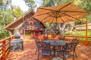 A wooden deck with outdoor furniture, a barbecue grill, and a large umbrella. - ROMANTIC LOG CABIN ~ Quiet, Clean, Cozy ~Walk to Trails, 3 Min to Town! (Idyllwild-Pine Cove)